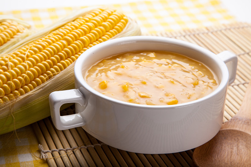 Uma tigela de caldo quente é apresentada em destaque, com aparência cremosa e textura encorpada.